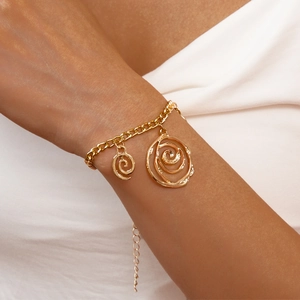 Detail of adjustable gold link bracelet featuring two textured spiral circle pendants