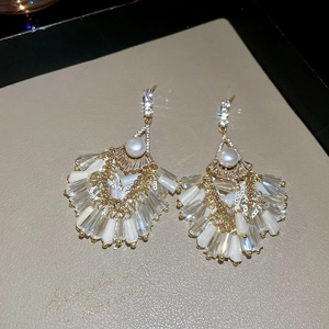 Close-up of fan-shaped vintage gold earrings with pearls, crystals and tassel details
