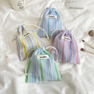 Close-up of four pleated striped drawstring pouches in yellow, blue, pink, and green colors