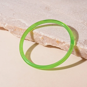 Détail macro d'un bracelet en résine vert émeraude translucide sur une surface en pierre