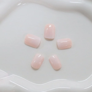 Pink gradient press-on nails with white polka dots and floral design on ceramic plate