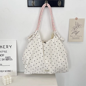 Détail du sac cabas en toile avec motifs de cœurs noirs et poignées tissées colorées