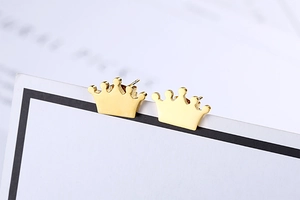 Detailed macro view of golden crown stud earrings showing smooth metallic finish and texture