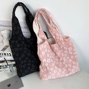 Detail shot of 3D floral lace embroidery on pink and black fabric shoulder bags