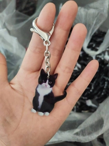 Detailed macro view of acrylic black and white tuxedo cat keychain with metal clip