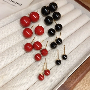 Detail of multi-size red and black spherical stud earrings set on a jewelry tray