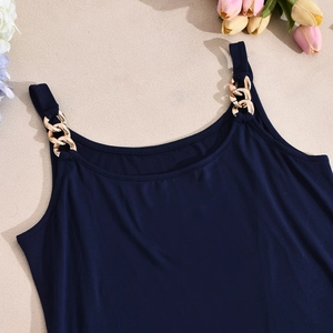 Detail von marineblauem Top-Set mit dekorativen goldenen Metallketten-Trägern auf Stoff