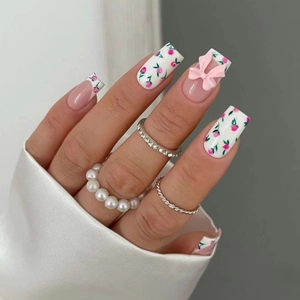 Detailed view of pink floral press-on nails with 3D bows and rose patterns on a hand