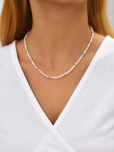 Close-up of irregular baroque pearl necklace with gold beads on female model collarbone