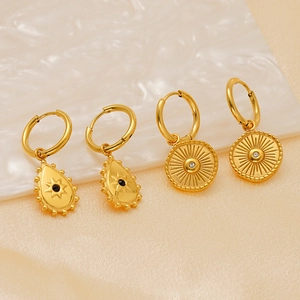 Close-up of 18K gold plated earrings with teardrop black gemstone and textured round charms