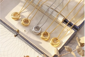 Detailed view of oval pendant necklaces in gold and silver finish on a jewelry box