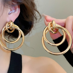 Détail de boucles d'oreilles créoles triple anneaux dorés au design superposé