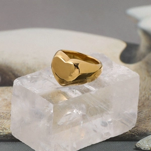Detailed view of an 18K gold heart-shaped ring displayed on a clear crystal base