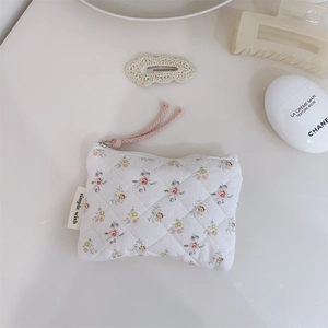 Détail d'une pochette en coton matelassé fleuri avec fermeture éclair et étiquette