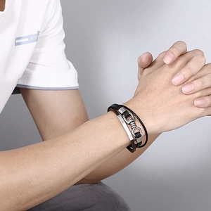 Gros plan d'un bracelet en cuir multicouche avec boucles métalliques sur poignet masculin