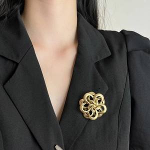 Elegant gold camellia flower brooch pinned on a black blazer for a luxury fashion look