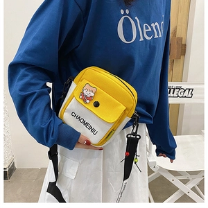 Detail of yellow and white canvas crossbody bag with cute bear patch and strap