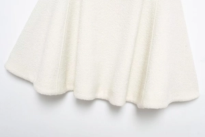 Detailed view of the white wool blend fabric hem with textured tweed finish on elegant cape coat