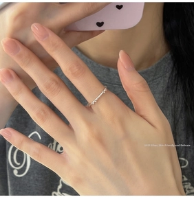 Detail of delicate S925 sterling silver hollow bow ring worn on index finger