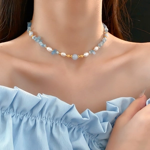 Détail d'un collier de pierres bleues et perles porté au cou pour un style plage