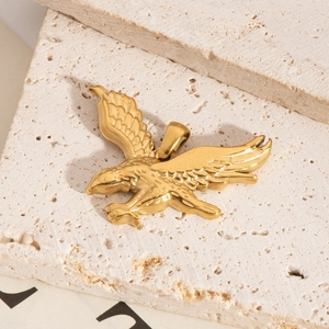 Détail d'un pendentif aigle doré aux ailes déployées sur fond de pierre naturelle