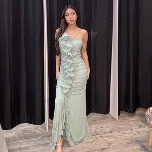 Détail de robe longue vert clair à une épaule avec volants et fente latérale haute