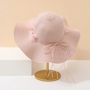 Détail d'un chapeau de paille rose montrant le tissage, fleurs mousseline et perles