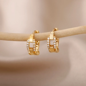 Macro shot of gold U-shaped hoop earrings with white zircon on a wooden display