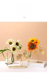 Detailed view of golden ginkgo leaf metal frame with a glass tube vase for home decor
