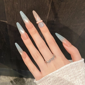 Macro shot of long stiletto press-on nails with pink to blue ombre and 3D bow detail