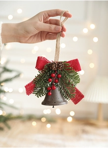 Detail of Christmas metal bell with pine cones, red berries and burlap bow decoration