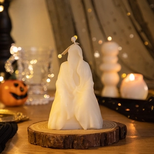 Ghost-shaped white scented candle on wooden base with festive pumpkin background