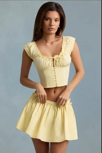 Detail of yellow floral two-piece set featuring ruffled crop top and pleated mini skirt