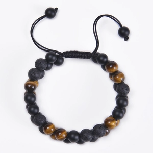 Detailed macro view of 8mm tiger eye and matte volcanic stone beads on braided bracelet