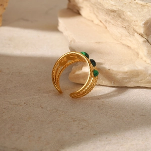 Detail of gold hollow open ring with three green malachite stones on a stone background