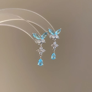 Dettaglio di orecchini a farfalla in argento con gemme azzurre e pendente a goccia