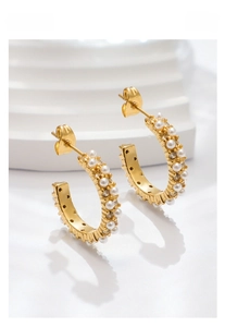 Detail of 18k gold C-shaped earrings featuring white pearls and zircon embellishments