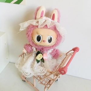 Rosa Plüschpuppe in weißem Spitzenkleid und Hut in einem rosa Mini-Einkaufswagen