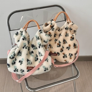 Detail of floral lamb wool tote bags with woven handles and a brand leather patch