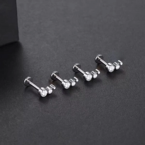 Macro view of four silver titanium labret studs with triple crystal stone cluster design