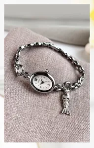 Macro detail of GEDI oval watch featuring a silver chain strap and a small fish pendant
