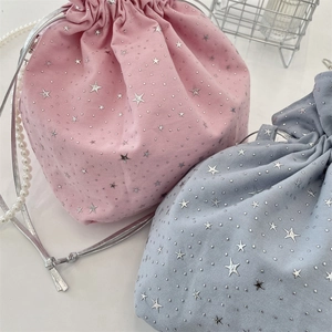 Detail of pink and blue canvas drawstring bags with silver star patterns and pearl chains