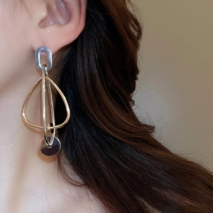 Détail macro de boucles d'oreilles géométriques multicouches en métal doré et argenté