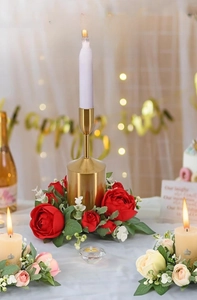 Detail of red rose wreath with golden candle holder and white taper candle decor