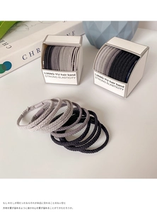 Macro detail of high-elasticity braided hair bands in neutral tones and white gift box
