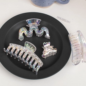 Macro detail of iridescent laser hair claws in wavy and bear shapes on black tray