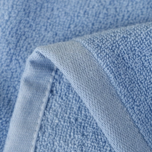 Close-up of high-density cotton loops and neat stitching on light blue kids towel