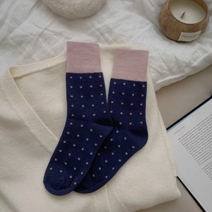 Close-up of blue and pink polka dot crew socks on cozy knitted cardigan background