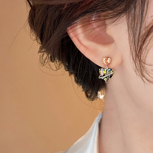 Green and orange heart-shaped planet stud earrings with metallic planetary rings on model