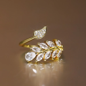 Close-up of golden leaf ring with marquise-cut zircons and elegant mirror reflection